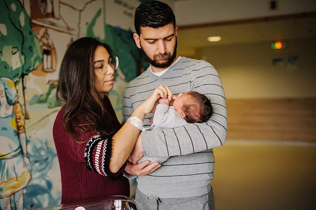 New parents holding their newborn baby in a hospital